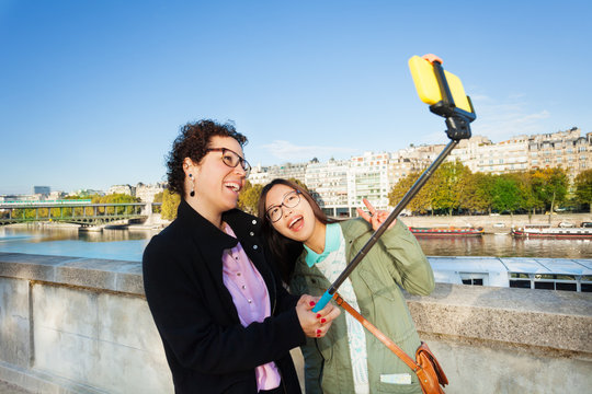 Cheerful tourists taking selfie photo with stick