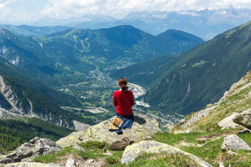 Fototapeta na wymiar Woman sits on the top on the mountain, Montblanc, exciting the view