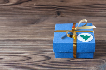 Blue gift box with golden ribbon on a brown wooden background for Christmas and New Year