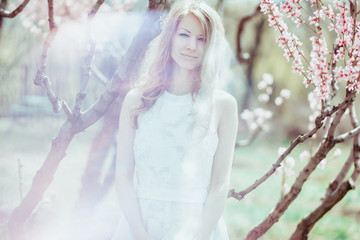 Beautiful spring blond girl in blooming tree
