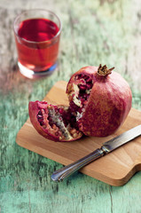 Fresh pomegranate juice and pomegranate. Pomegranate and glass of pomegranate juice on a wooden textural background. Healthy drink. Red Green