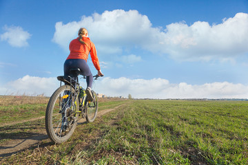 Fototapeta premium Bike riding - woman riding on a bicycle in nature offroad. Sport and fitness concept.