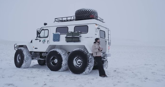 A tired traveler leaning on his trecol car and drinking hot tea.  Yamal 4k