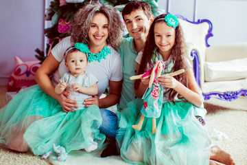 The mother,father  with daughters sitting near christmas tree