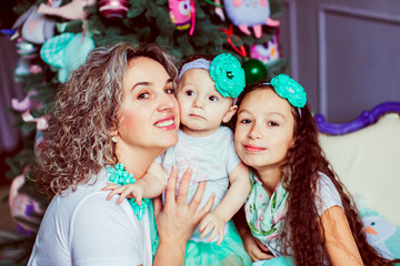 The mother  with daughters sitting near christmas tree