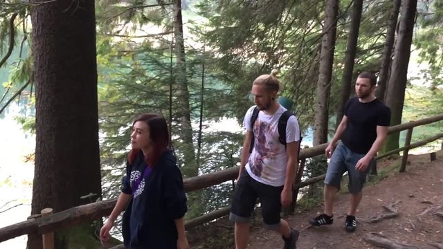 Group of tourists goes along the lake in Carpathian mountains. Slow motion.