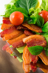 Detail of a plate of fried bacon and  cherry tomatoes