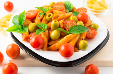Italian pasta penne in tomato sauce with olives and cherry tomat