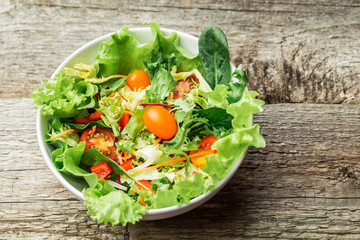 Salad with fresh vegetables - tomatoes, carrots, bell peppers and mixed greens - arugula, mesclun, mache.