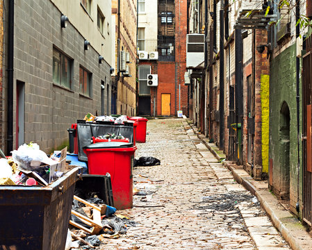 Fototapeta Looking down an inner city alleyway full of garbage and wheelie bins