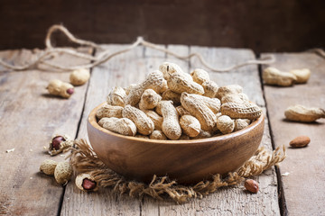 Peanuts in shell in a wooden bowl, selective focus
