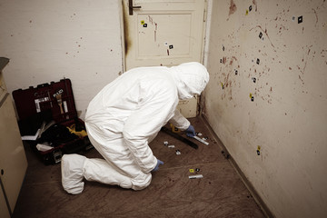 Criminologist technician collecting evidences on crime scene