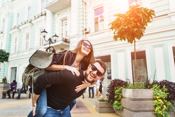 Man and woman travelers walk in the city. Happy couple laughing and hugging. A bearded man with a backpack on his shoulders. A girl holds a bottle with water.