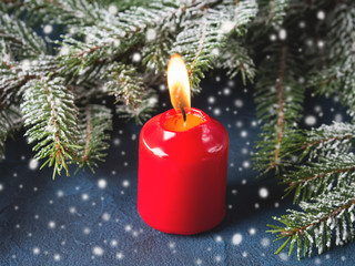 Dark christmas background with red candle and fir tree branches. Snow effect