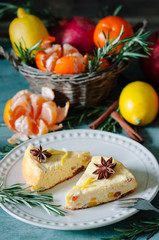 Winter breakfast on a wooden table cottage cheese casserole with tangerines, pomegranates, lemons, rosemary and cinnamon sticks