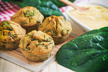 Vegan muffins with spinach and corn flour on wooden background