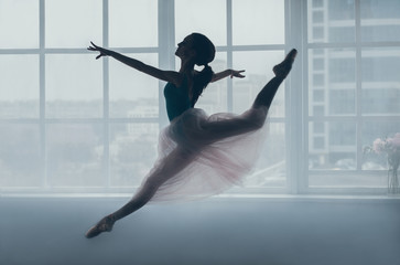 Ballerina in the jump in front of a window