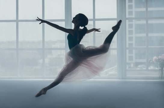 Fototapeta Ballerina in the jump in front of a window