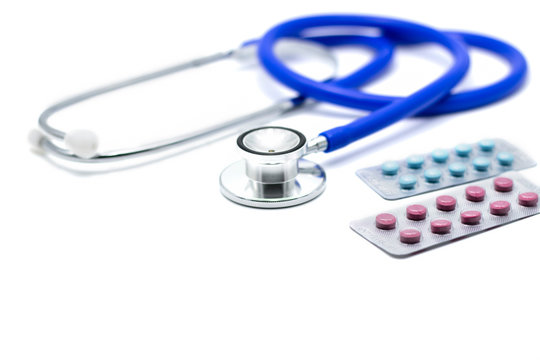 Medical pills on doctor desk with stethoscope.