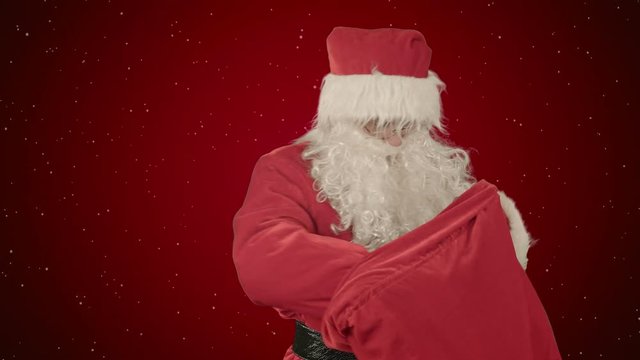 Real Santa Claus carrying presents in his sack on red background with snow