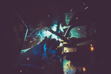 Industrial workshop man welding round pipe on a metal work table,making a lot of colorful smoke, sparks and reflections