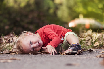 Happy one year old boy playing in the leaves