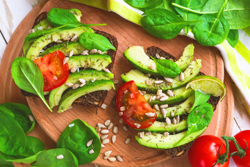 Toast with sliced avocado, tomatoes, spinach and spices