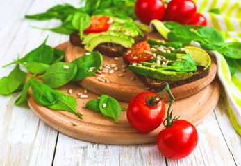 Toast with sliced avocado, tomatoes, spinach and spices