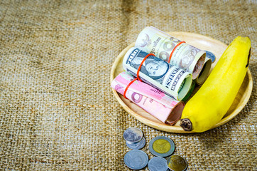 banknotes and banana in wooden tray, easy investment concept