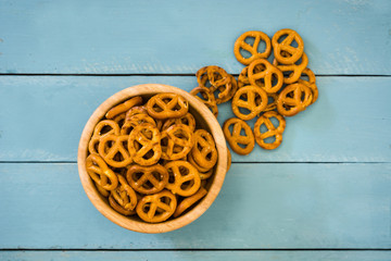 Salted pretzel in bowl on blue wooden background