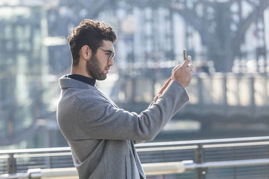 Young businessman taking picture with smartphone
