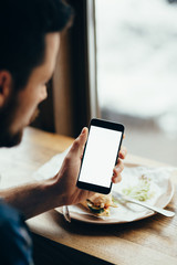 Young man looking at phone, sitting at the restaurant