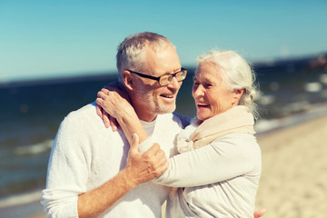 happy senior couple hugging on summer beach