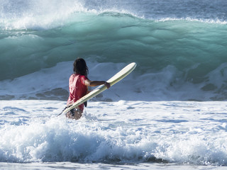 Girl practicing in the waves of the Atlantic ocean surfing, in f