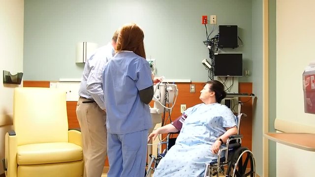 nurse and doctor in room with patient sitting in wheelchair
