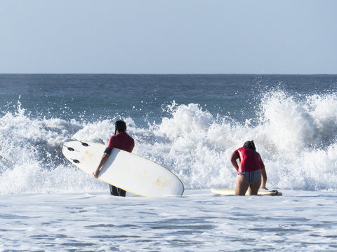 Boy And Girl Practicing In The Waves Of The Atlantic Ocean Surfi