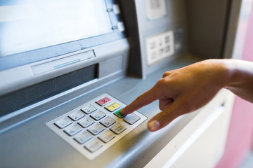 close up of hand entering pin code at atm machine