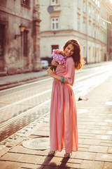 The beautiful girl with bouquet stands in the center of street