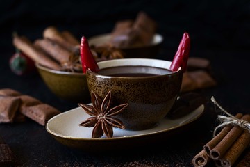 Cup of hot chocolate with chili pepper on dark wooden background