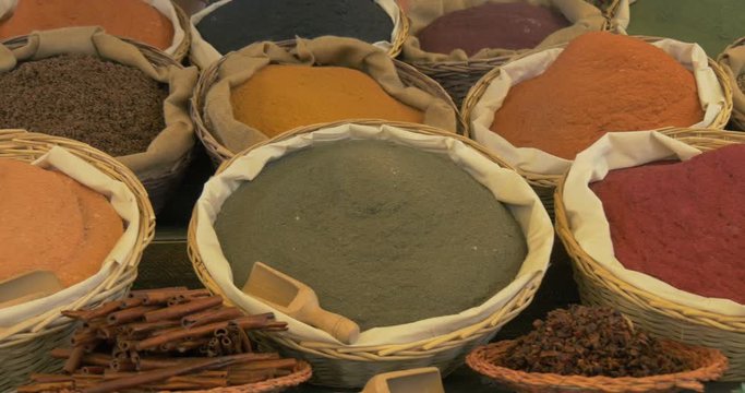 Different spice in baskets and sacks on wooden shelf
