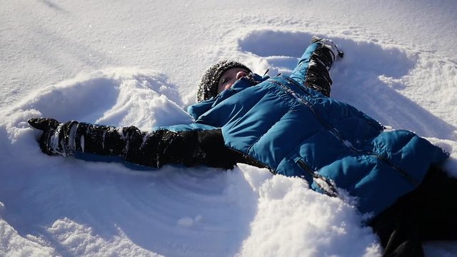 the baby lies on snow and making a snow angel in slowmotion