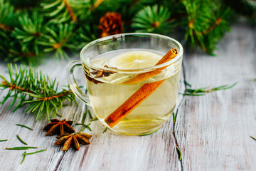 a mug of tea with lemon and cinnamon sticks star anise Christmas theme