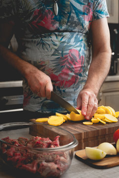 Cutting raw potatoes for baking with meat