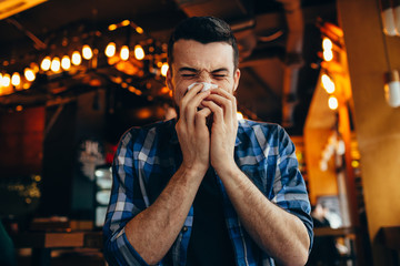 Attractive young man blowing his nose