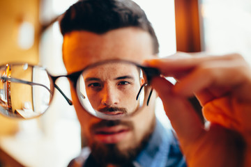 Closeup portrait of young man with glasses, who has eyesight problems