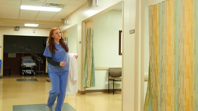 Doctor walking down hallway hastily to patients room with coat in arm

