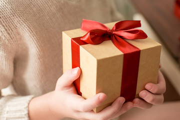 Christmas gift with red bow in the hands of a child