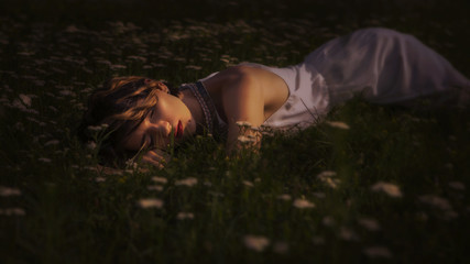 Beautiful brunette woman sleeping in a grass and flowers in the