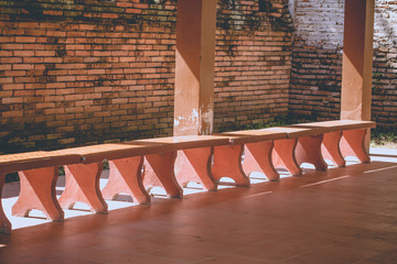 Empty red cement bench at the historical temple wall with light and shadow