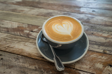 Coffee cup with heart shape latte art on wood table at café